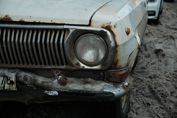 Detail shot of a rusty headlight on an old abandoned car. Texture-rich image symbolizing aging, neglect, and time.