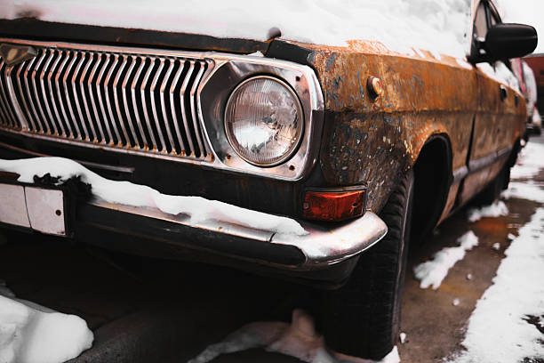 Old rusty vintage car parked on snowy city street. Strong urban decay and nostalgia concept.