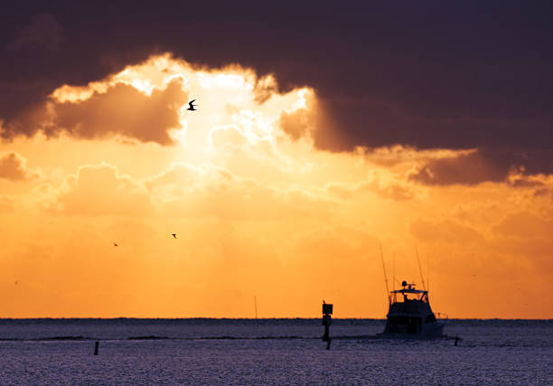 Amazing Clouds and Sky during a Morning Sunrise over the Atlantic Ocean with fisherman, dolphin birds and the moon. Whale Harbor inlet in Islamorada, Florida.