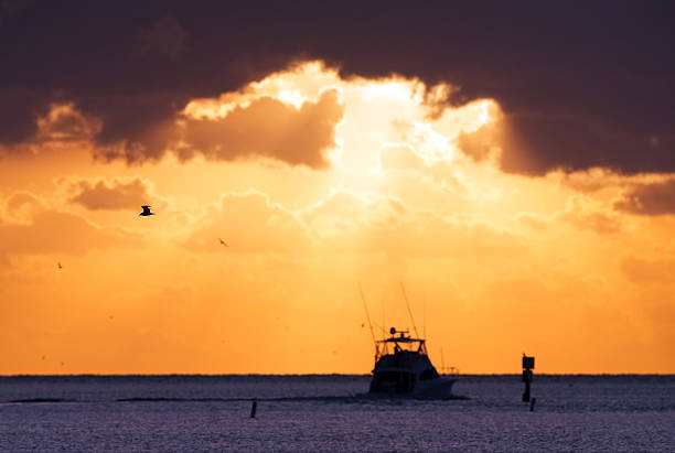 Amazing Clouds and Sky during a Morning Sunrise over the Atlantic Ocean with fisherman, dolphin birds and the moon. Whale Harbor inlet in Islamorada, Florida.