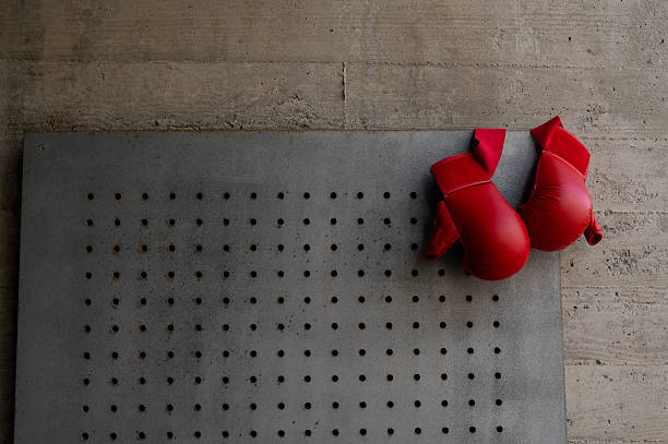 Two red boxing gloves are on a gray surface.