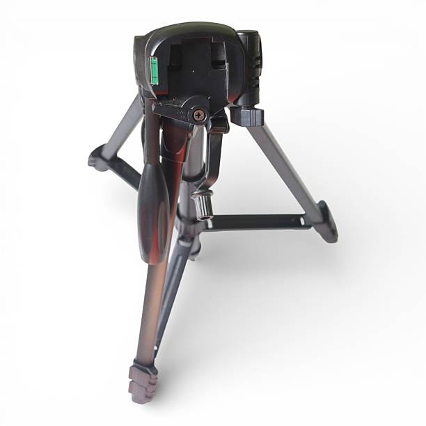 The image shows a black camera tripod with a shiny metallic leg The tripod has a center column head with a screw for adjusting camera height and angle stability The tripod has three legs with a metallic texture The background is white