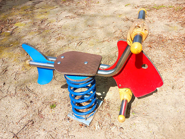 Seesaw in horse shape, children outdoors playground toy in the sunlight.
