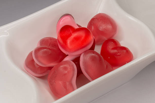 Bright red jelly hearts served in a white dish, isolated on a white background. Perfect for desserts, candy, and food photography.