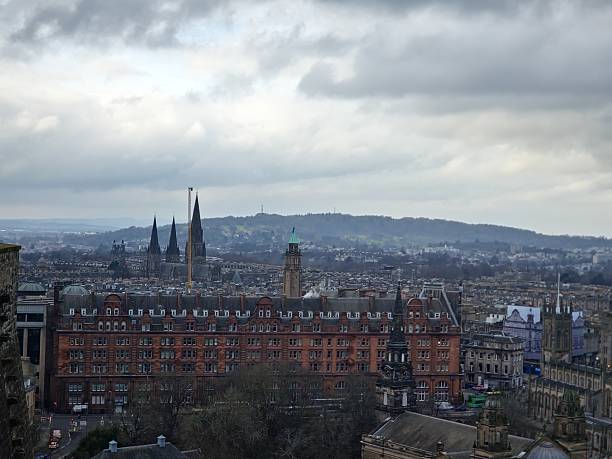 Wide panoramic view of a Scottish city seen from a high mountain viewpoint with natural scenery.