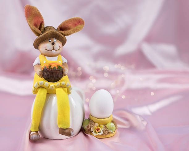 Easter bunny with egg in yellow cup on light pink blurred background. High quality photo