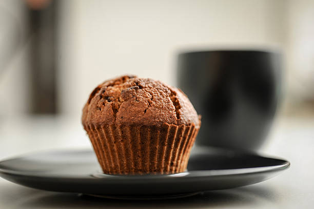 Muffin with chocolate cream and coffee next to the window for breakfast
