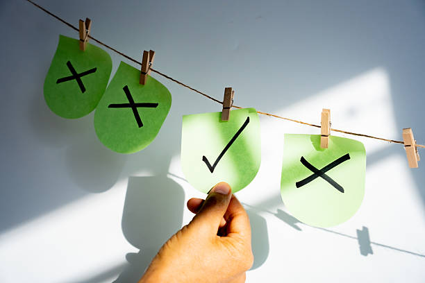 Hand selecting a green sticky note with a black checkmark among other notes with crosses, representing decision making process