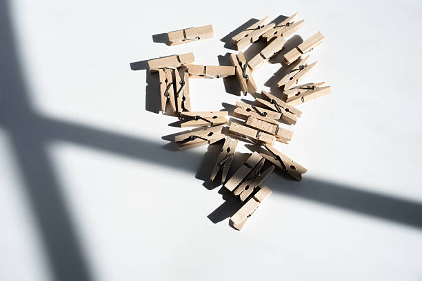 Wooden clothespins creating a heart shape, casting shadows, on a clean white surface. Showing romance, love, and organization