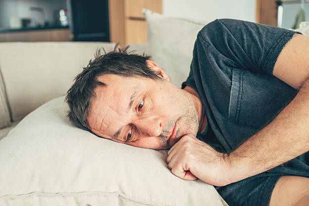 Sad young man with pillow at home