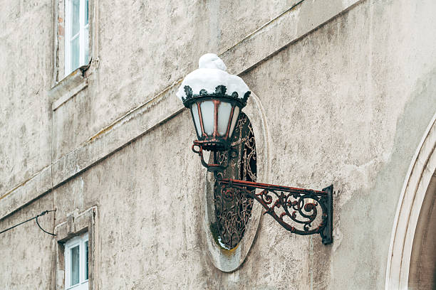 Ornate vintage wall lantern snow-capped in winter old town, selective focus