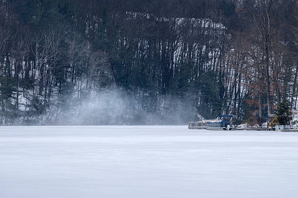 At a lakefront community in Tennessee strong wind gusts blow powdered snow off the top of a frozen lake, providing a frigid scene of frost and climate.