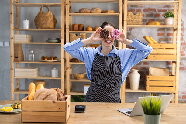 Playful baker holding donuts over eyes in bakery