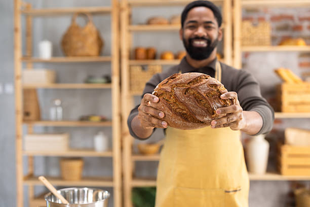 Baker holding fresh artisan bread smiling at camera