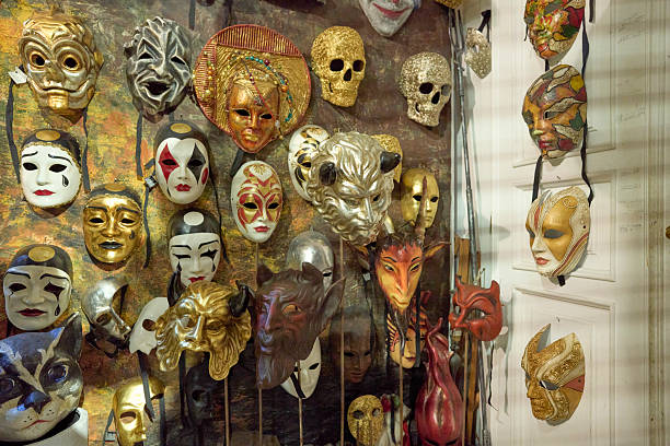 Many traditional and modern venetian carnival masks hanging on a wall and shelves, showing detailed artistry and craftsmanship