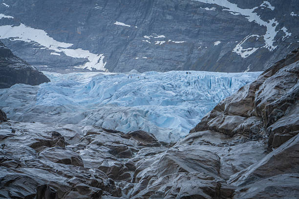 Dramatic view of Nigardsbreen glacier in Norway, showing blue ice formations, rugged rocks, and mountain landscape. Powerful symbol of climate change and raw nature.