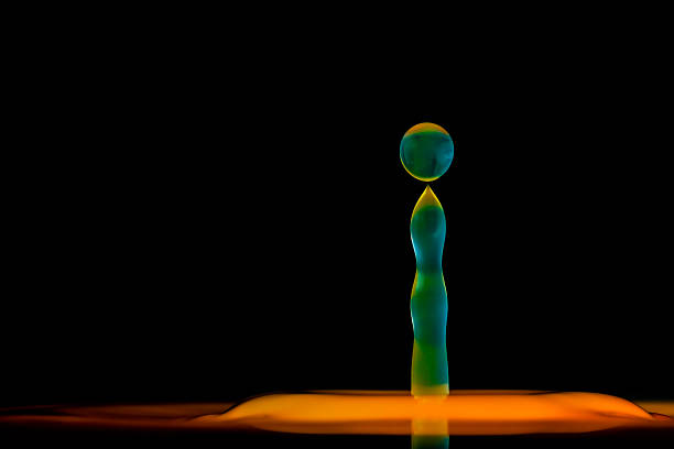 Close up macro color image depicting a colorful water drop splashing into a body of water, with ripples. Room for copy space.