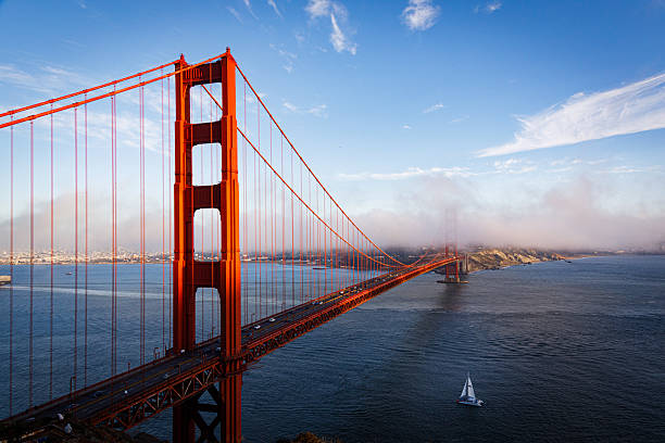 An astonishing an colorful sunset view of the Golden Gate Bridge with a small ship (catamaran) sailing on the right