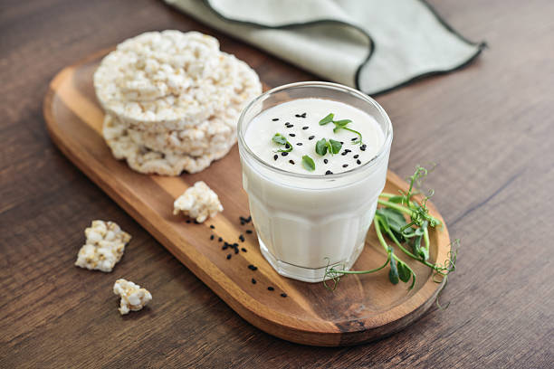 Homemade natural kefir or ayran with rice cakes in a glass on wooden background, closeup
