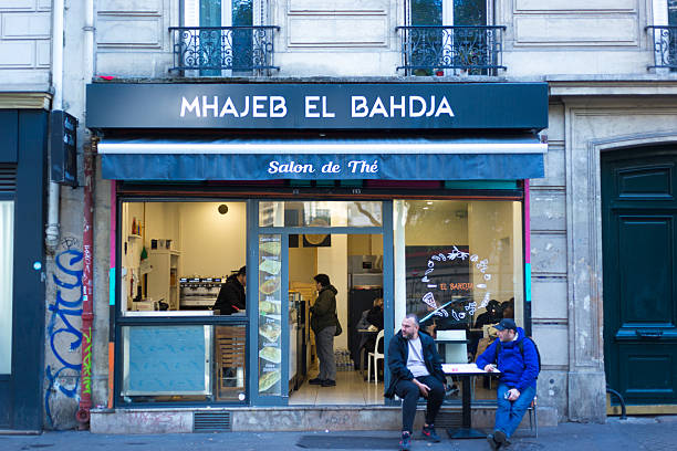 Paris, France - October 27, 2025: Two mature men sit outside a North African tea salon on Blvd de Belleville, which forms the border between the 11th and 20th arrondissements.