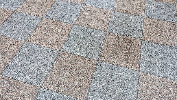 Close-up of gray and beige granite tiles arranged in a grid pattern on the floor