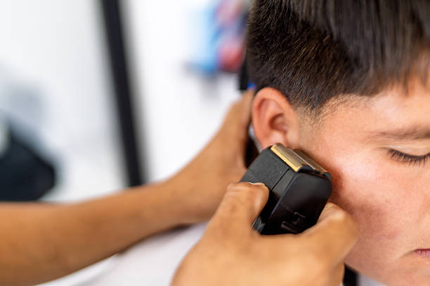Professional barber trimming a male customer's hair with an electric clipper, providing a fresh haircut in a barbershop