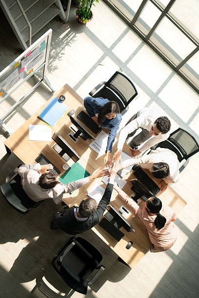 Top view of a multicultural business team stacking hands together over a meeting table