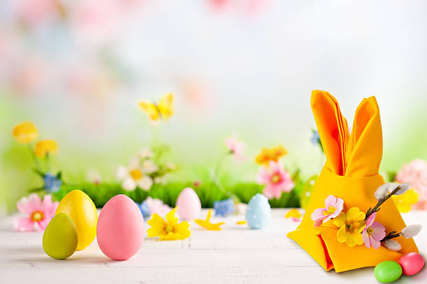 A table with a yellow napkin and three eggs on it. The napkin is folded into a bunny shape