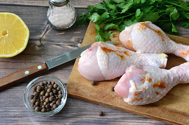 Fresh Raw Chicken Drumsticks with Herbs and Spices on Wooden Board