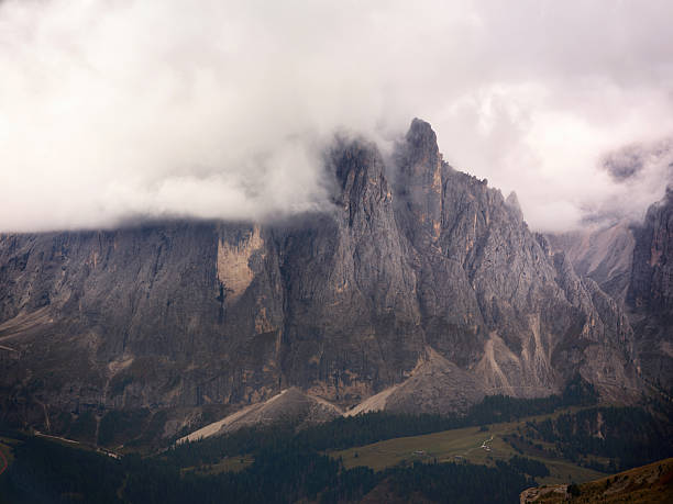 Steep Langkofel mountain peaks in the Italian Dolomites with dramatic clouds surrounding them. Photographed in medium format.