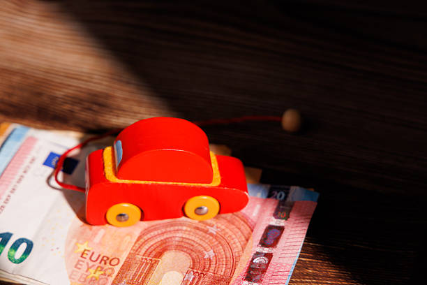 European car affordability crisis with a wooden toy car on Euro bills. Ideal for representing banking loans, auto finance and expensive rentals.