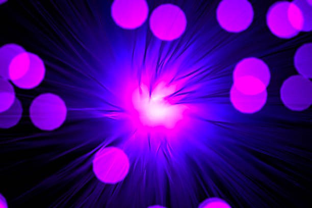 Close-up view of optical fiber cables glowing with blue light against a solid black background, creating an abstract pattern of soft, circular bokeh highlights and bursts of brighter illumination. The image captures the essence of data transmission and digital connectivity through luminous strands that evoke streams of information flowing in a high-tech environment. Ideal for illustrating concepts in telecommunications, internet infrastructure, big data, AI, and futuristic innovation in business and science publications. The horizontal composition emphasizes the complexity and beauty of fiber optic technology without any people or identifiable objects, focusing on the ethereal, glowing orbs that suggest speed and global communication networks. Suitable for editorial use in articles on digital transformation, cybersecurity, and engineering advancements.