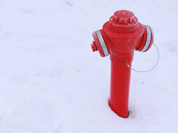 Red fire hydrant standing in fresh snow during winter. Strong contrast of bright red and white, minimal composition, clean background, visible texture of frost and snow. Concept of safety infrastructure, urban winter, emergency services, copy space.