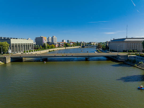 Bridge Over Odra River in Wroclaw, Poland. Bridge crossing the Odra River in Wroclaw, Poland. Aerial view showing a green steel bridge, riverbanks, park area, and surrounding urban architecture on a sunny day. European city scene highlighting transportation, travel, and city infrastructure.