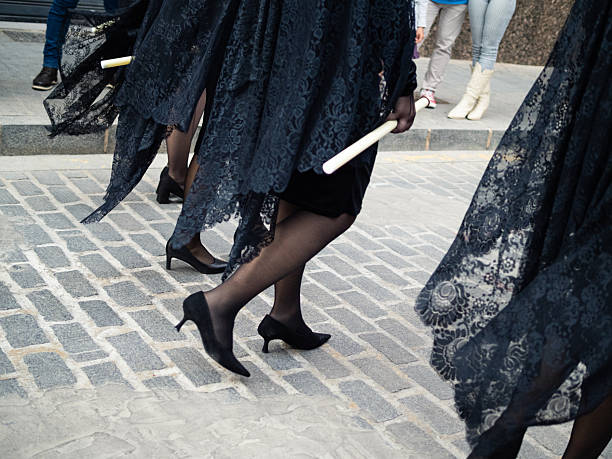 Manolas women in black lace mantillas and high heels walking during a religious procession