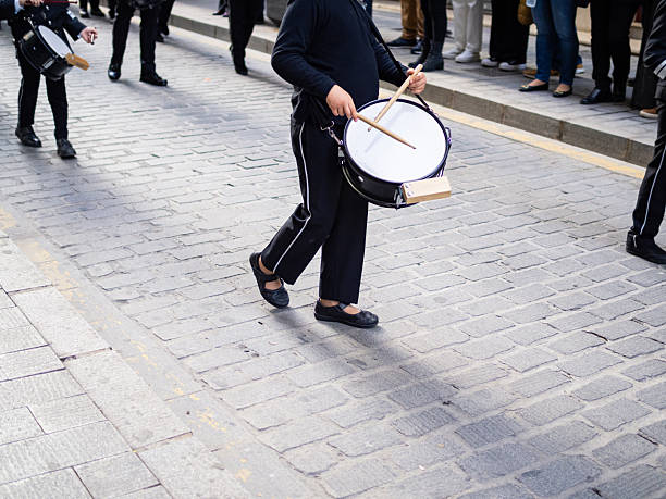 Child playing a drum during traditional Holy Week procession on cobblestone street