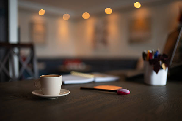 Coffee cup sits on a wooden desk, notebook open and smartphone nearby. Creating a productive home office workspace.