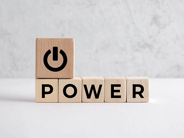 Wooden blocks forming the word POWER with a power switch icon resting on top, representing power on or power off concepts.