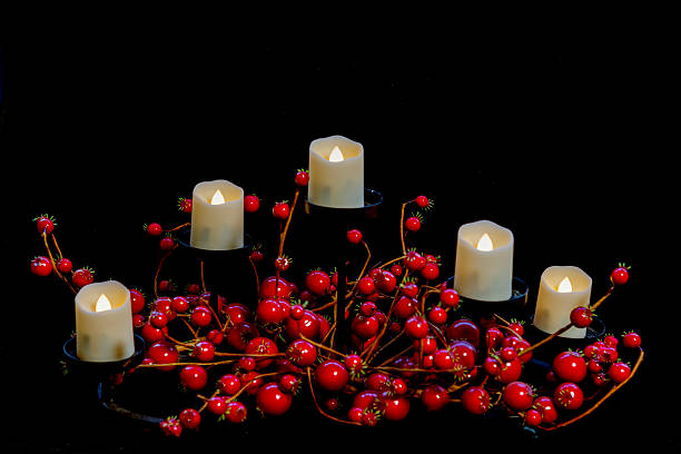 A black Christmas candlestick holder adorned with red berries on a black background with lots of copy space.