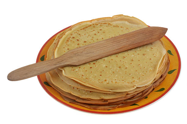 Plate of freshly made crepes on stove in kitchen, closeup