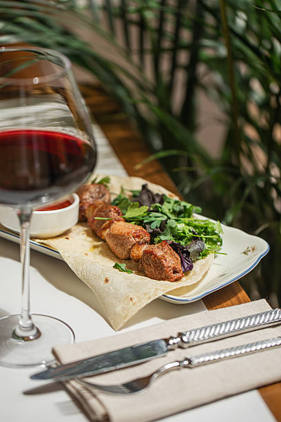Caucasian lamb shashlik with red sauce and marinated onions served on flatbread with herbs