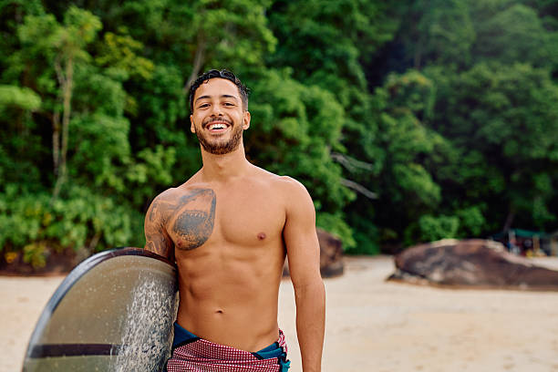 Young male surfer with his surfboard on the beach