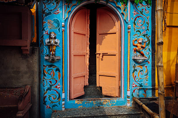 Vibrant blue and turquoise temple facade with pink open doors, ornate sculptures, and floral motifs; a vivid glimpse of Indian cultural heritage in Varanasi.