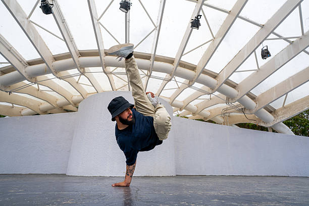 Male breakdancer performing a difficult move balancing on one hand with his leg extended upwards