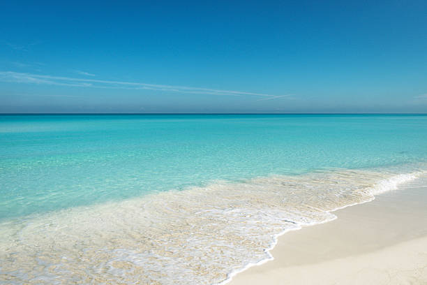 Pristine Varadero beach in Cuba featuring turquoise shallow waters, white sand, and a calm horizon under a bright blue sky. Ideal for travel, relaxation, and tropical vacation visuals.