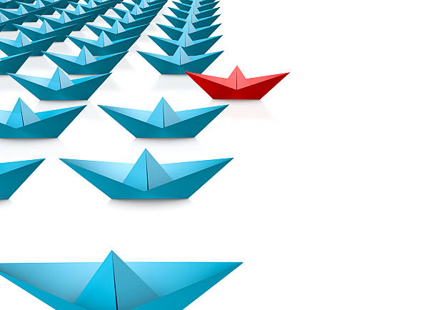 Leadership concept with red paper ship leading among blue on white background