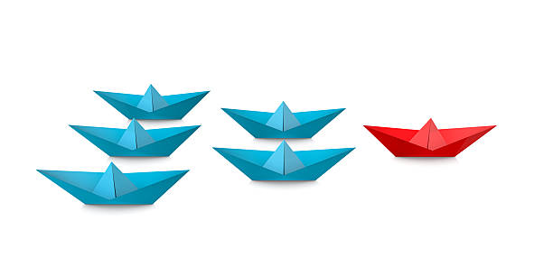 Leadership concept with red paper ship leading among blue on white background