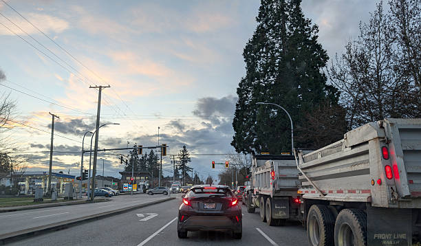 Surrey, Canada - February 6, 2026: Looking west as traffic waits on 96th Avenue in the Fleetwood-Tynehead neighbourhood. Gas stations and small retailers to the left at 160th Street. Dramatic sky over Metro Vancouver.