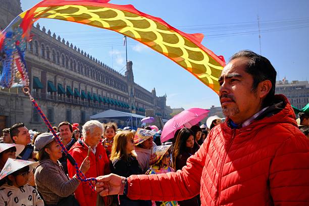 Mexico City, CDMX, Mexico – February 7, 2026: A man in a red jacket holds a dragon dance pole as spectators gather in the historic center of Mexico City.