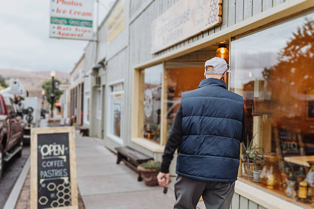 A  senior man walks through the historic downtown district of Maupin, Oregon and looks in shop windows while on his way to buy his morning coffee from a local cafe.